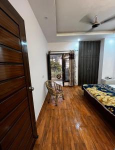 a bedroom with a bed and a chair and a door at The Retreat Base in Rājpur