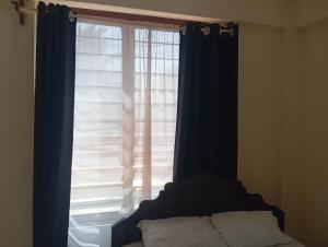 a bedroom with a large window with blue curtains at Nest Apartment Diani in Diani Beach