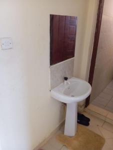 a bathroom with a white sink and a shower at Nest Apartment Diani in Diani Beach