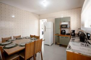 a kitchen with a table and a white refrigerator at Casa Aconchego da Bisa - perto do Estádio do Operário! in Ponta Grossa