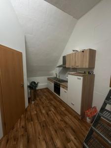 an empty room with a kitchen with wooden floors at Monteurwohnung, 1 Zimmer Apartment in Bad Essen
