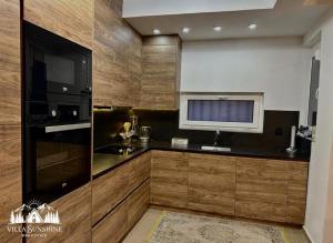 a kitchen with wooden cabinets and a black refrigerator at Villa Sunshine Brezovicë in Brezovica