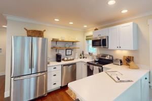 a kitchen with white cabinets and a stainless steel refrigerator at Steps to Riverfront: Dtwn Bluffton Studio! in Bluffton