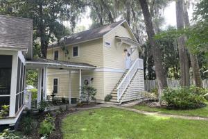 a woman standing on the stairs of a yellow house at Steps to Riverfront: Dtwn Bluffton Studio! in Bluffton
