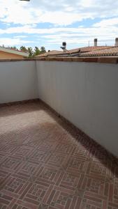 a balcony with a white wall and a brick floor at Casa Grazia Deledda 16 in Orosei