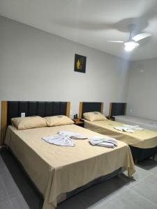 two beds in a hotel room with towels on them at Hotel Porto Real in Pôrto Real