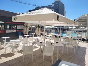 a patio with tables and chairs and an umbrella at Topaz Hotel in St. Paul's Bay