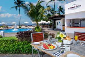 a table with a bowl of fruit on it next to a pool at Ocean Breeze Nuevo Vallarta in Nuevo Vallarta