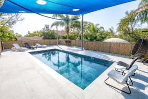 a swimming pool with chairs and an umbrella at Nesbehadnes in Had Nes