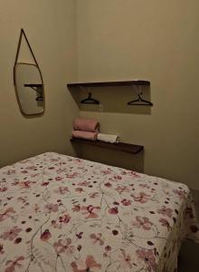 a bedroom with a bed with a floral bedspread and a mirror at Casa Corrupião - Ilha do Ferro - Alagoas in Pão de Açúcar