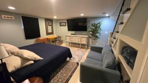 a bedroom with a bed and a couch and a tv at Clinker Cottage Garden Apartment - Free Breakfast! in Albany