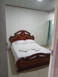 a bed with a wooden headboard and two books on it at CASA HOTEL EL PRADo in Mesetas