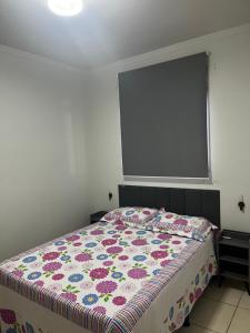 a bedroom with a bed with a floral comforter at Apto 2 quartos, Wi-Fi rápido, Self check in in Uberlândia