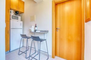 a kitchen with two chairs and a small table with a refrigerator at Vilamar 2 - Madeira Inn Group in Calheta +10 photos