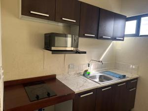 a kitchen with a sink and a microwave at Depa Pakabtun Descansa sin pagar de mas 2 hab wifi y AC in Mérida +14 photos
