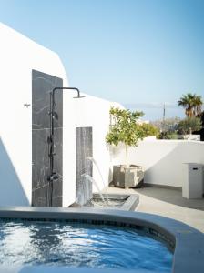 a swimming pool with a water fountain in front of a house at SN Santorini Apartments in Kamari