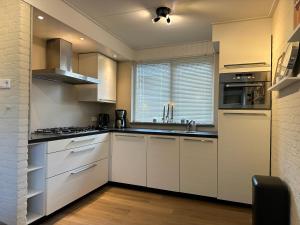 a kitchen with white cabinets and a sink at Vakantiewoning Hornzicht in Anjum