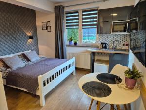 a bedroom with a bed and a table and a kitchen at VILLA MILA Apartamenty in Karpacz