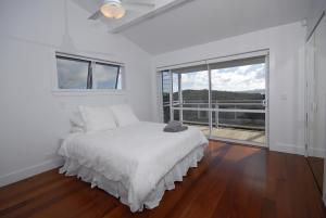 a white bedroom with a bed and a large window at Wharau Lodge in Kerikeri