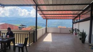a woman sitting at a table on a balcony at Hotel y parqueadero La Colonia Inn in Socorro