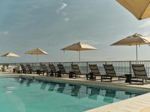 a row of chairs and umbrellas next to a swimming pool at Ambros Daytona, Trademark Collection by Wyndham in Daytona Beach