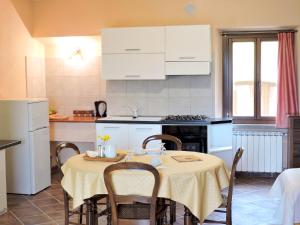 una cucina con tavolo, sedie e armadietti bianchi di Casale Fedele Family Relax B&B Vicino al Borgo a Ronciglione