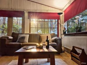 a living room with a couch and a table at Chalet Bosrust met serre & privéparking Natuur nabij Maastricht in Lanaken