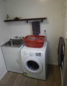 a washing machine with a sink and a basket on top at One Pigeon Takatu in Tawharanui