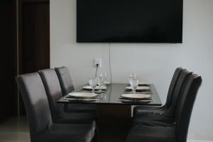 a dining room table with black leather chairs and a television at casa com piscina in Sinop