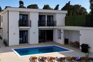 a house with a swimming pool in front of it at White Villa, Brac in Splitska