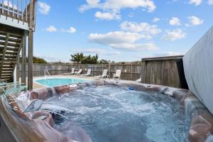 a hot tub in a backyard with a swimming pool at 8180 - Looney Dunes in Waves