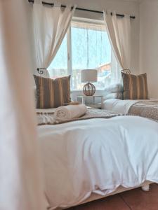 two beds in a bedroom with a window at Dan en Wan in Agulhas +10 photos