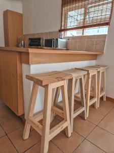 a kitchen with a wooden counter with three stools at Dan en Wan in Agulhas