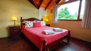 a bedroom with a bed with red sheets and a window at Taiquen Apart Hotel in San Martín de los Andes