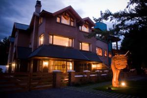 a house with a wooden cat statue in front of it at Taiquen Apart Hotel in San Martín de los Andes