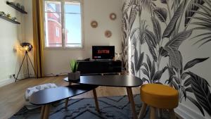 a living room with a table and a tv at Le Petit Jacobin - City center in Beauvais