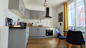 a kitchen with white cabinets and a table and chairs at Le Petit Jacobin - City center in Beauvais +7 photos
