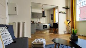 a living room with a couch and a kitchen at Le Petit Jacobin - City center in Beauvais