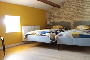 two beds in a bedroom with a brick wall at Gîte des forgerons in Sainte-Ouenne
