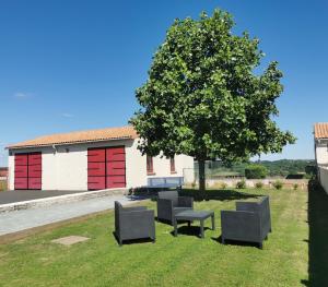 a group of chairs and a tree in the grass at Gîte des forgerons in Sainte-Ouenne