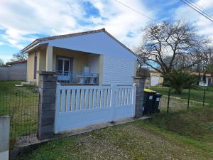 a white fence in front of a house at Petite maison calme in Queyrac
