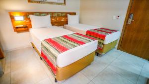 a room with two beds and a door to a bathroom at Meu Hotel Boituva in Boituva