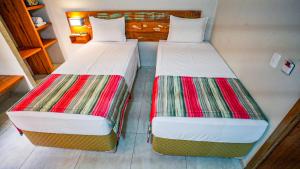 two beds sitting next to each other in a room at Meu Hotel Boituva in Boituva