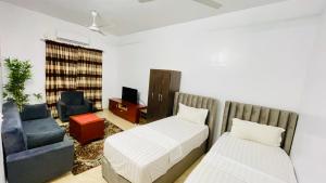 a bedroom with two beds and a couch and a chair at LeLodge Djibouti in Djibouti