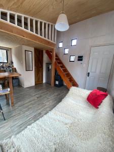 a bedroom with a large white bed and a staircase at Tiny House en Malalcahuello - Tranquilidad total in Malalcahuello