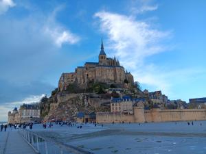 a castle on top of a mountain with people on the beach at Chambres d'hôtes de l'Eau dit Sée in Cuves