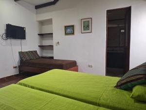 a bedroom with a green bed and a couch at Green Park Urbarí in Santa Cruz de la Sierra