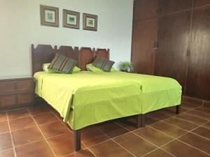 a bed with a green blanket on top of it at Green Park Urbarí in Santa Cruz de la Sierra