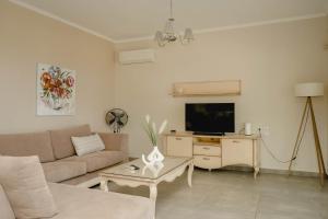 a living room with a couch and a tv at Pargamaisonnette in Parga