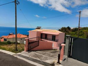 a pink house with the ocean in the background at Golden Sun Refugio -Calheta in Estreito da Calheta